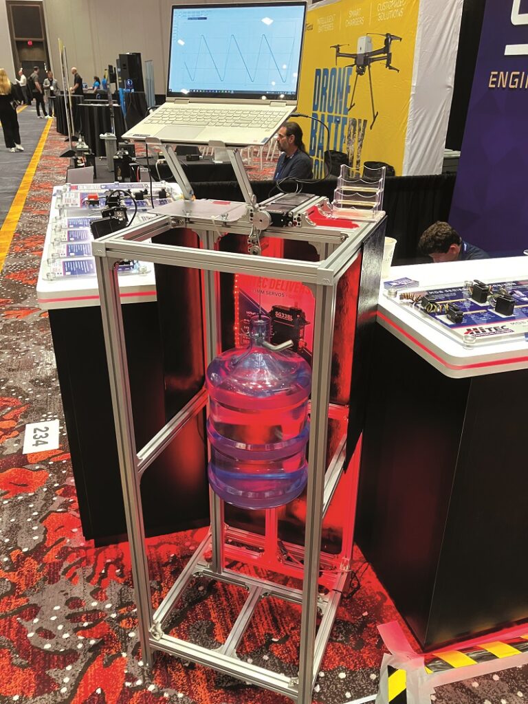 Hitec’s servo durability demonstrator lifts and lowers a heavy water bottle